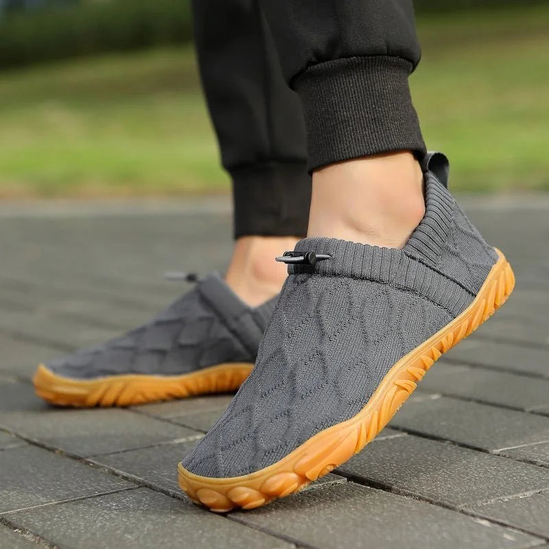 Grey barefoot-style shoes worn outdoors, side view