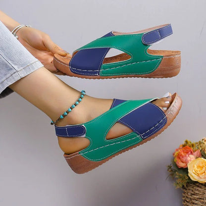 Green and blue criss-cross sandal shown on foot and held from the side