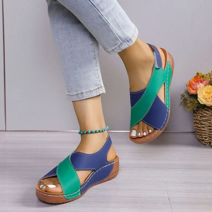 Green and blue criss-cross sandals worn indoors, front view