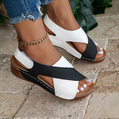 Black and white criss-cross walking sandals worn outdoors, side view