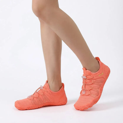 Coral orange lightweight walking shoes worn in a studio, side view