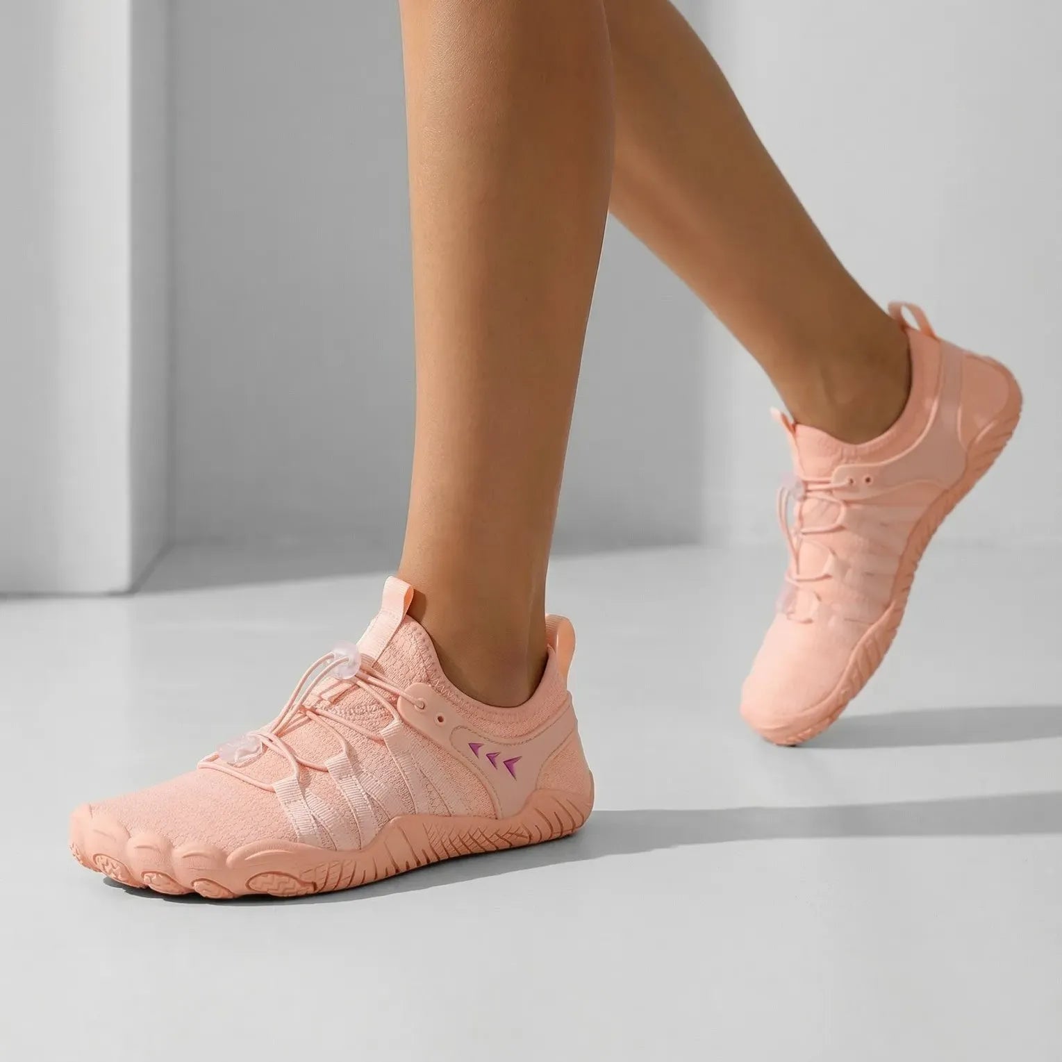 Dusty pink walking shoes worn in a studio, front and side view