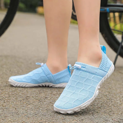 Blue barefoot-style shoes worn outdoors, side view