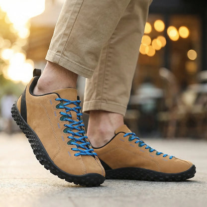 Tan wide toe walking trainers with blue laces worn from the side