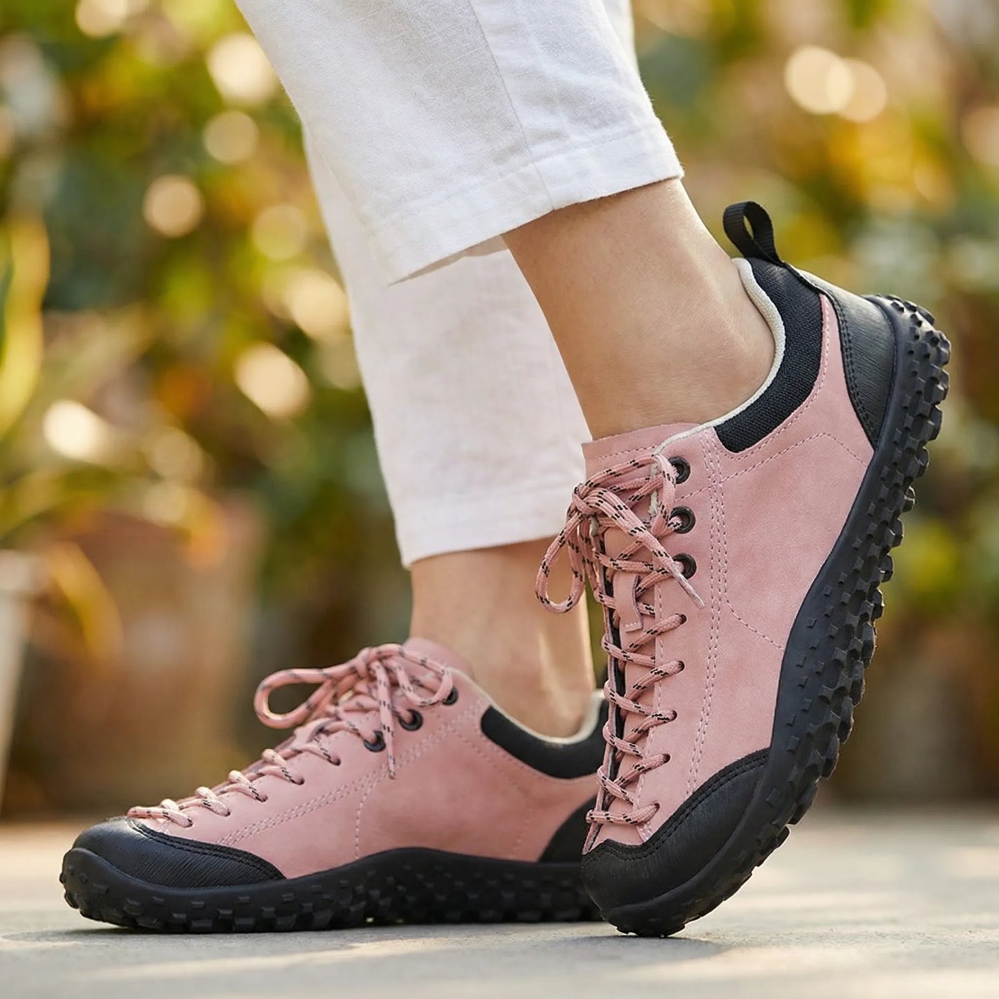 Pink wide toe walking trainers worn in side profile outdoors