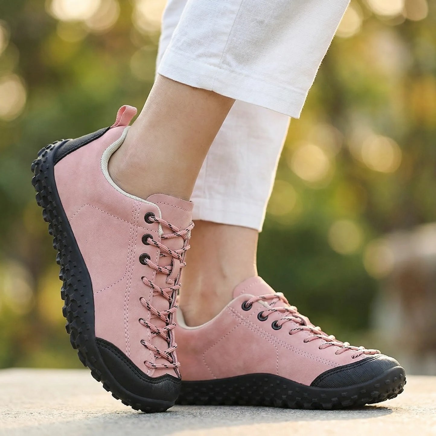 Pink wide toe walking trainers worn from the front outdoors