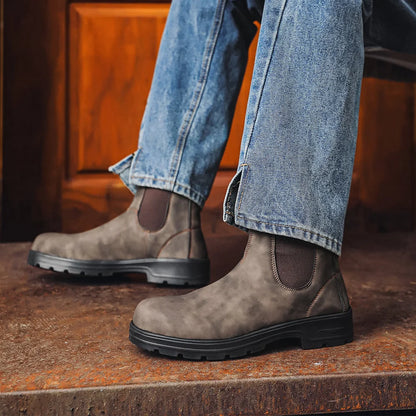 Grey Chelsea boots worn with blue jeans, side view