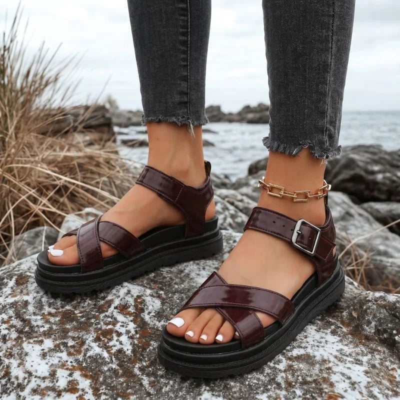 Women's brown cross-strap walking sandals worn outdoors from the side
