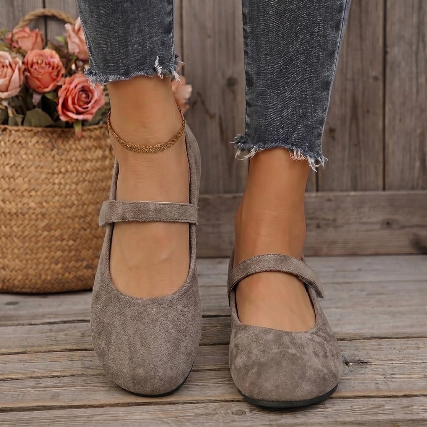 Women's taupe Mary Jane flats worn on a wooden deck, front view
