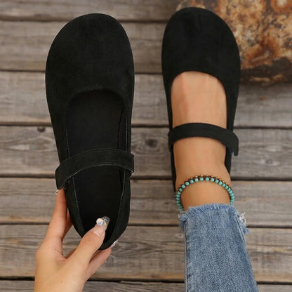 Women's black Mary Jane flats shown on foot with one shoe held