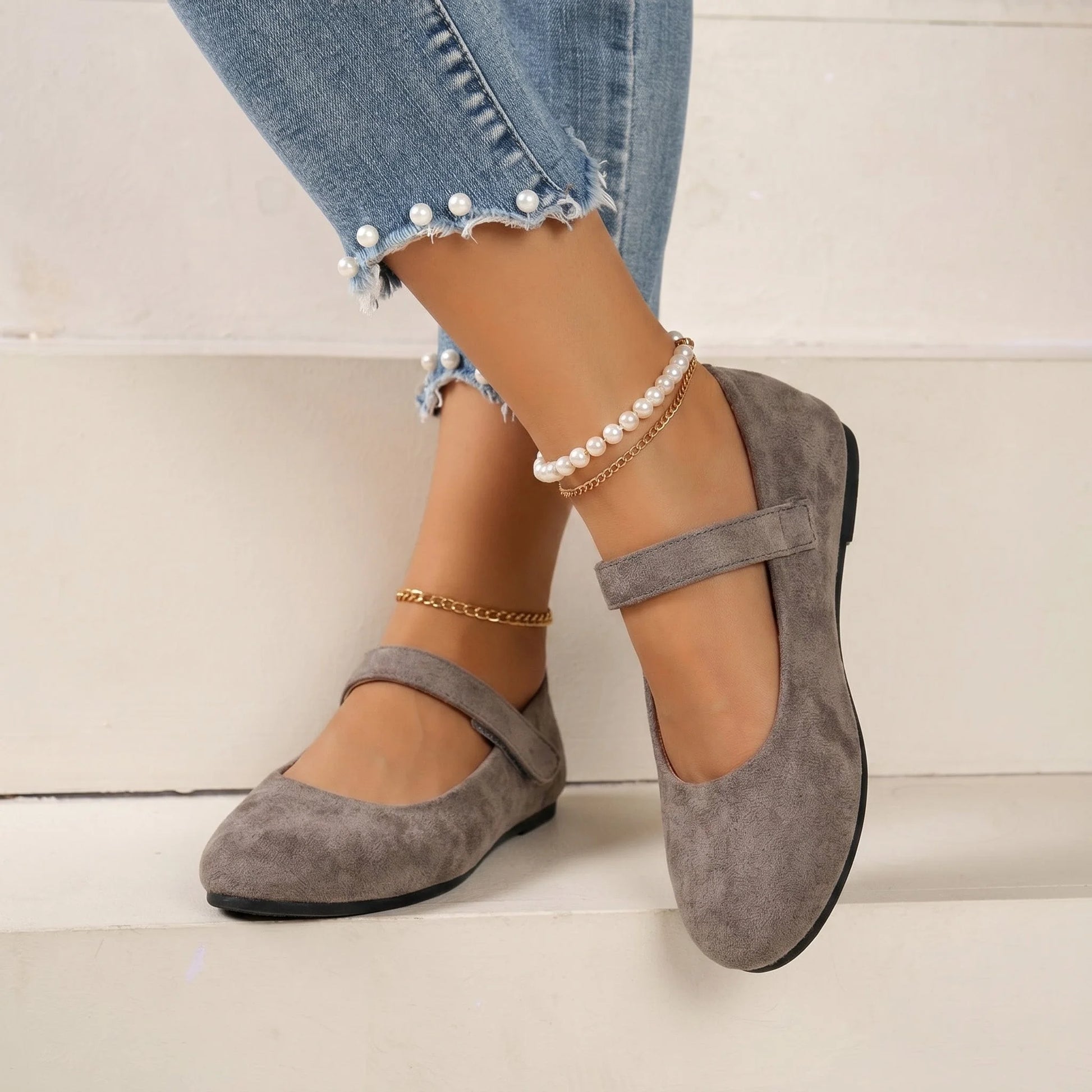 Women's taupe Mary Jane flats worn on steps, front three-quarter view