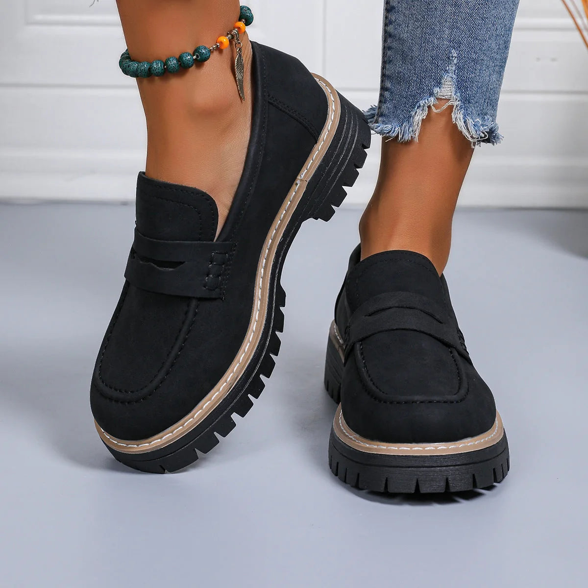 Black chunky sole loafers worn on foot, close side view