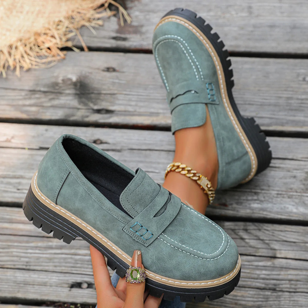 Dark green chunky sole loafer held in an outdoor setting
