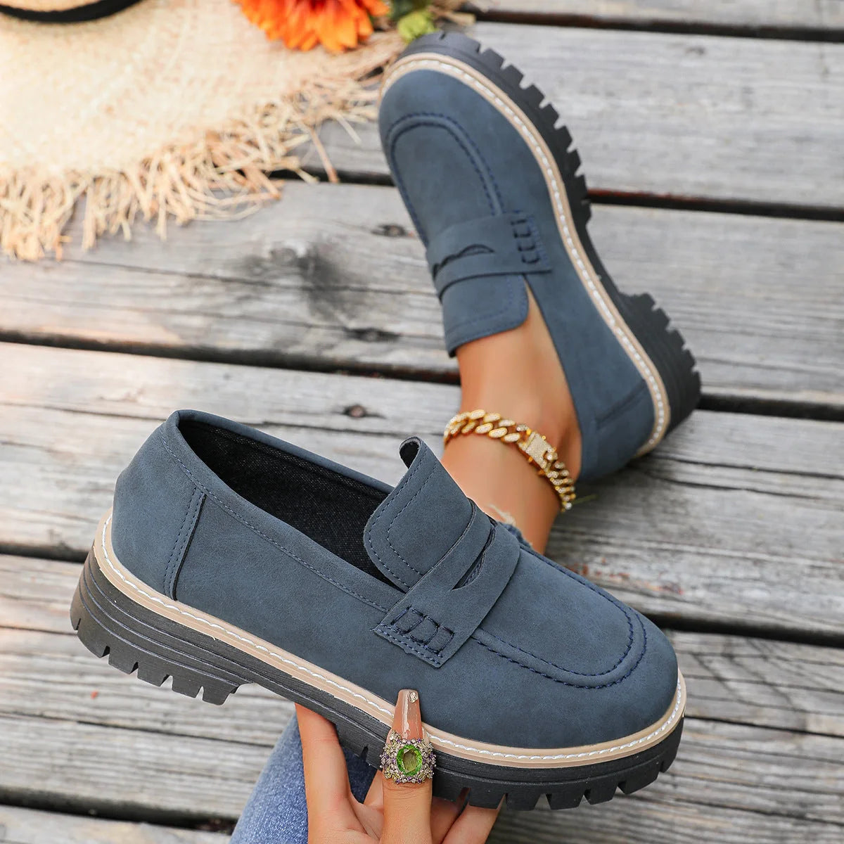 Blue platform loafers shown on foot and held from the side
