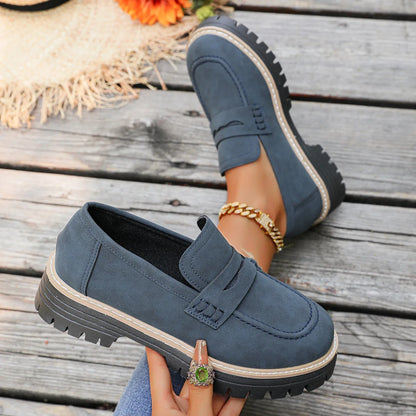 Blue platform loafers shown on foot and held from the side