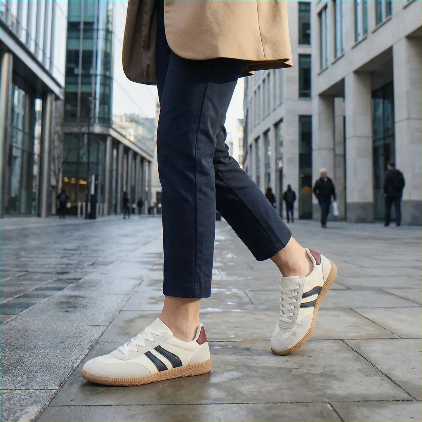 Woman wearing cream and navy trainers in the city