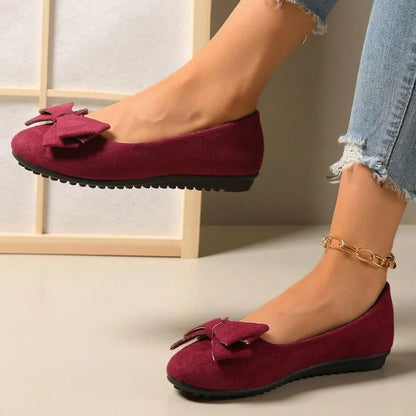 Women's burgundy bow ballet flats worn in side profile