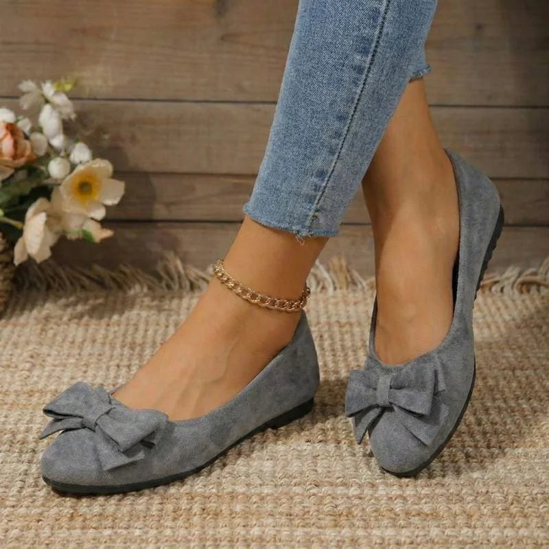 Women's grey bow ballet flats worn from the front