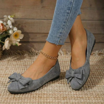 Women's grey bow ballet flats worn from the front