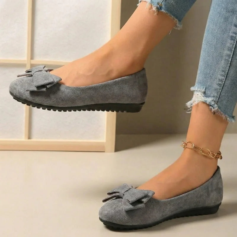 Women's grey bow ballet flats worn from the side