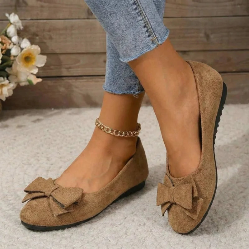 Women's tan bow ballet flats worn from the front