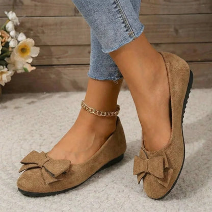 Women's tan bow ballet flats worn from the front