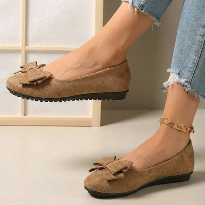 Women's tan bow ballet flats worn from the side