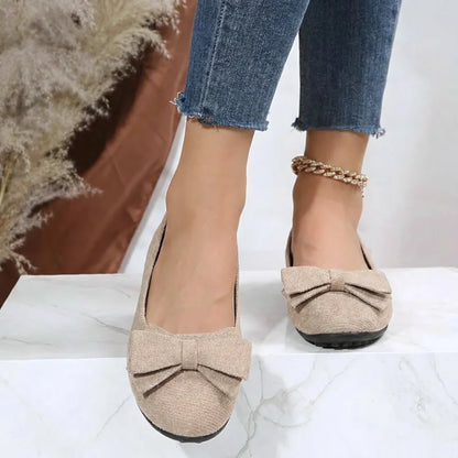 Women's beige bow ballet flats worn from the front