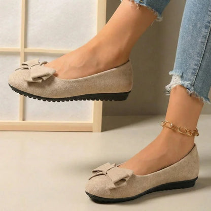 Women's beige bow ballet flats worn in side profile