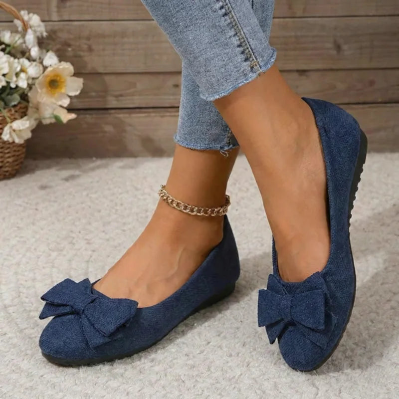 Women's navy bow ballet flats worn in a front three-quarter view