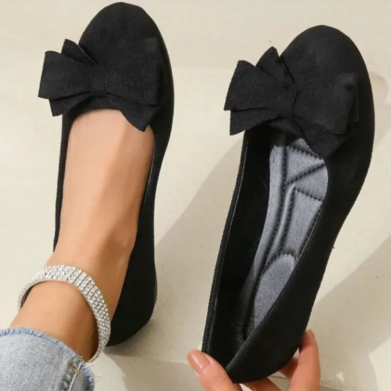 Women's black bow ballet flats shown on foot with the interior visible