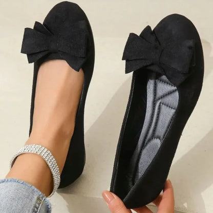 Women's black bow ballet flats shown on foot with the interior visible