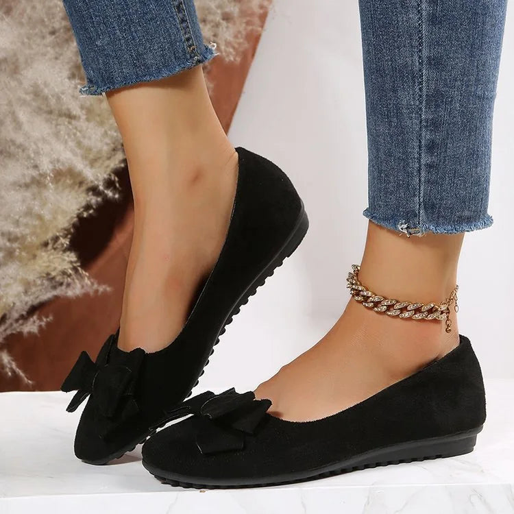 Women's black bow ballet flats worn from the side