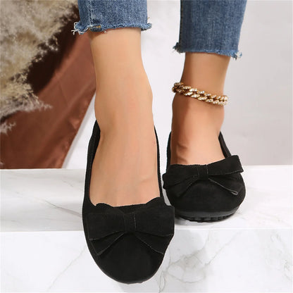 Women's black bow ballet flats worn from the front