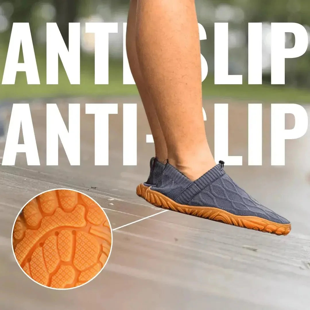 Grey barefoot walking shoe worn outdoors with orange tread detail