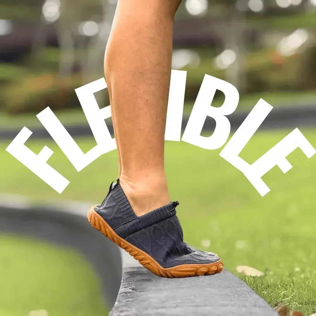 Grey flexible barefoot walking shoe bent at the forefoot outdoors